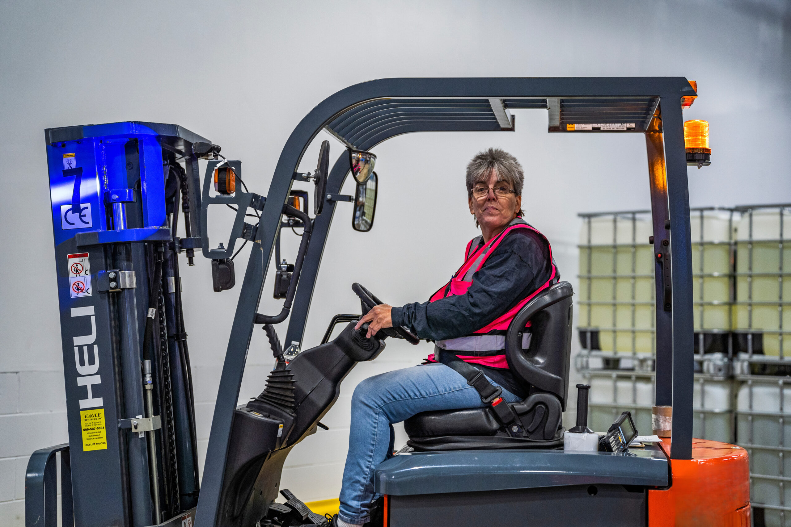 A woman operating a forklift from the driver's seat, focused and ready to handle heavy loads efficiently.