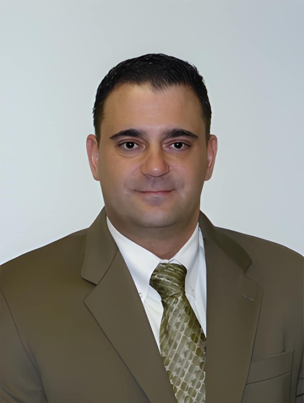 a man wearing a suit and tie smiling at the camera