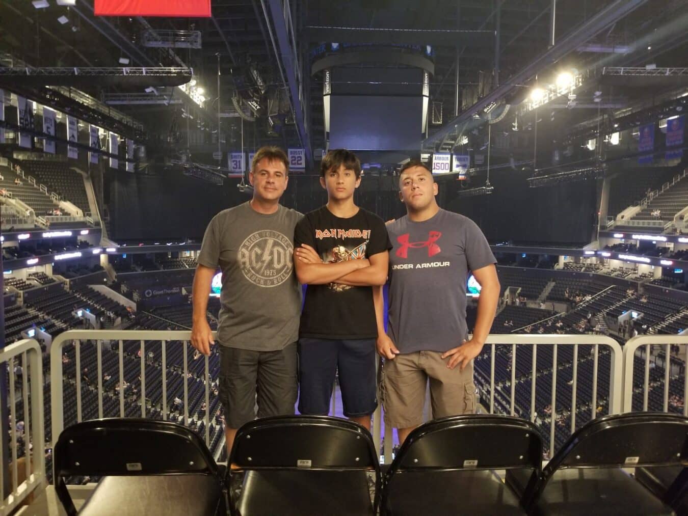 three men standing by their seats at a concert