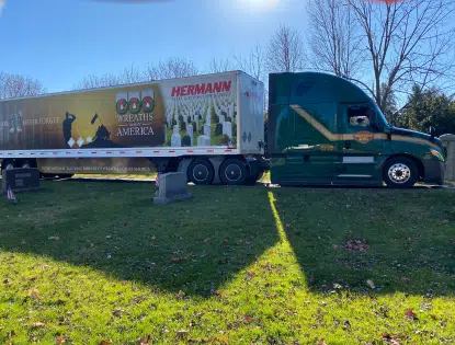 Trailer wrapped with Wreaths Across America's logo parked in a cemetery