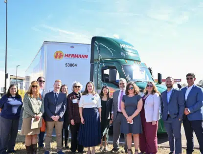 Group photo of people standing in front of an electric truck.