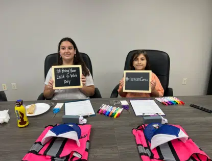 Two children sitting at a table holding chalkboards