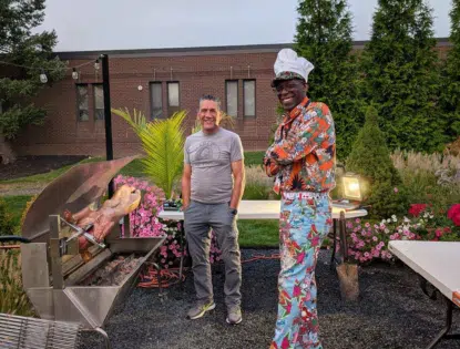 Two people outside standing near a pig fry